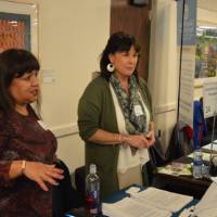 An alumna and a faculty member talk to a student about their field of study at the Academic Major Fair.